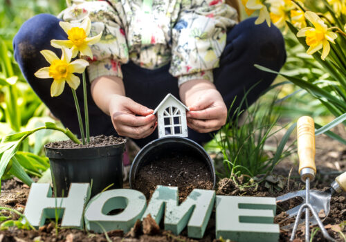 Earth Day .A child in the background of the garden holding a small wooden house. Wooden letters with the inscription home